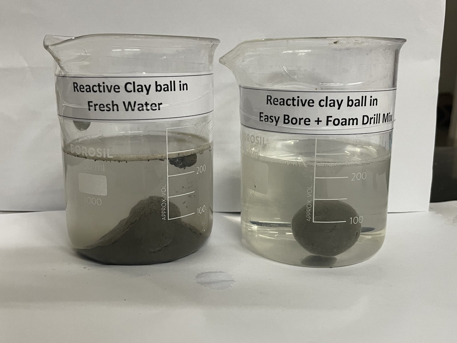 Two beakers side by side, a reactive clay ball in fresh water and a reactive clay ball in Easy-Bore™ + Foam-Drill™ mix: in the first the clay ball has slumped into a heap, in the second it is still whole