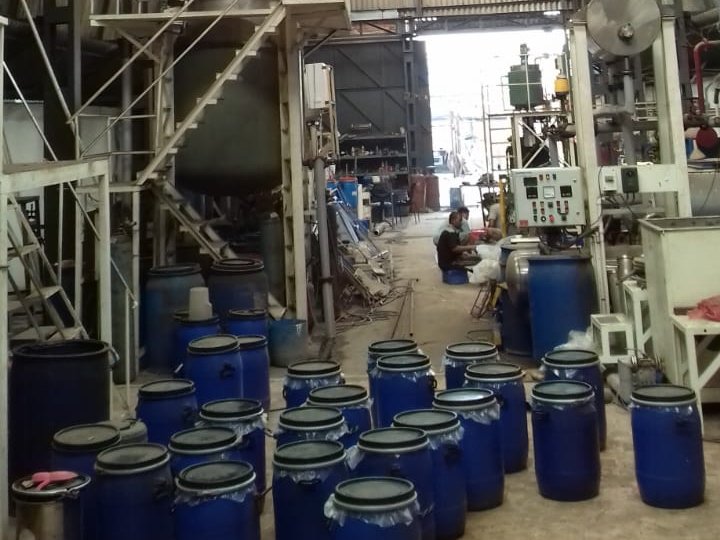 Blue drums on the floor of our polymer plant at Domjur, with the mixing platforms behind