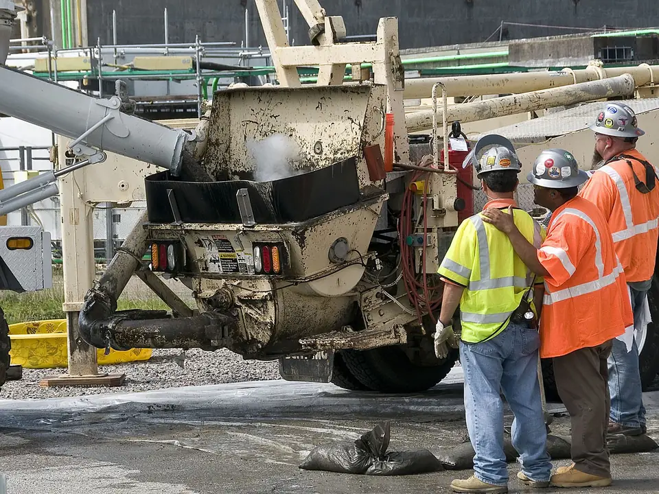 A mixer chute discharging grout into the hopper of a site grout pump
