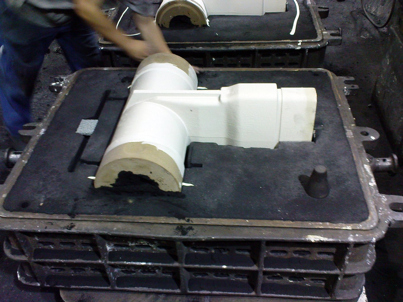 A foundry worker handling a pattern on a moulding box of sand
