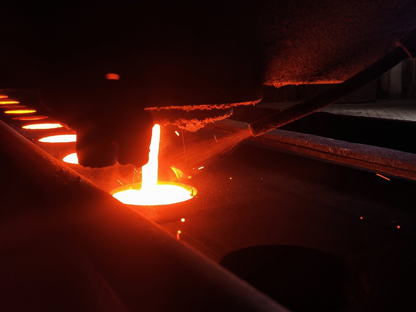 Molten cast iron running into a green sand mould on a foundry moulding line