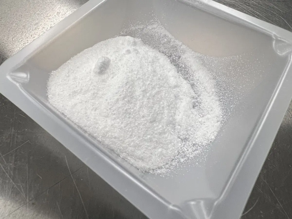 White free-flowing powder in a laboratory weighing dish
